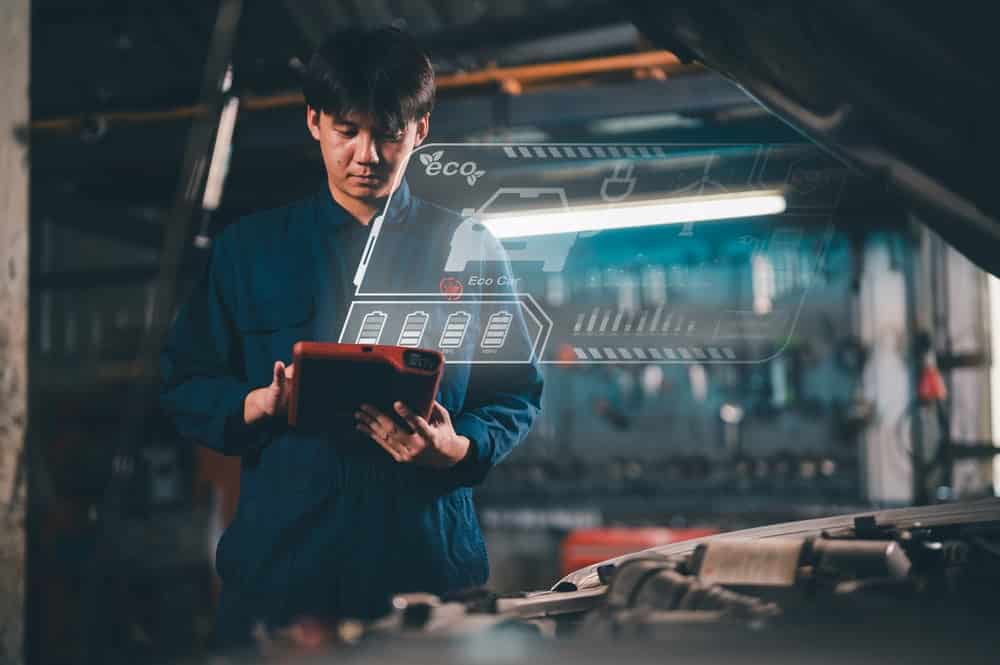 A mechanic uses a tablet to access digital vehicle dimension databases as part of car repairs.