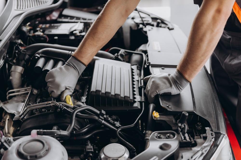 Un technicien réparant un véhicule dans un atelier de carrosserie, assisté d'un marbre encastrable avec double ciseaux de levage