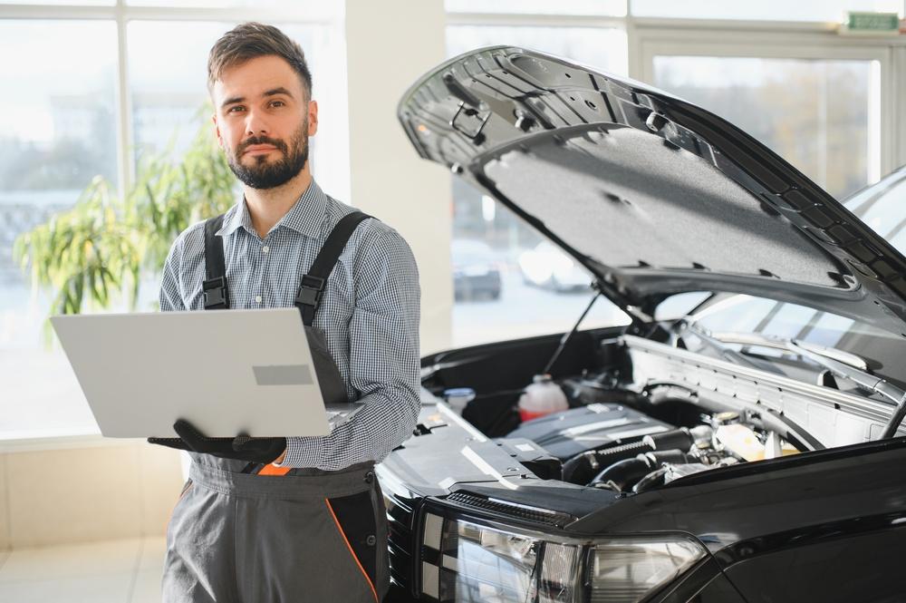 A certified body shop technician inspecting a vehicle, illustrating body shop certification standards.