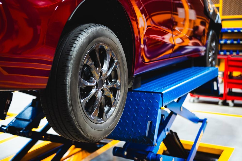 A car lifted in a car repair shop. A universal jig system makes it easier to work with different models.