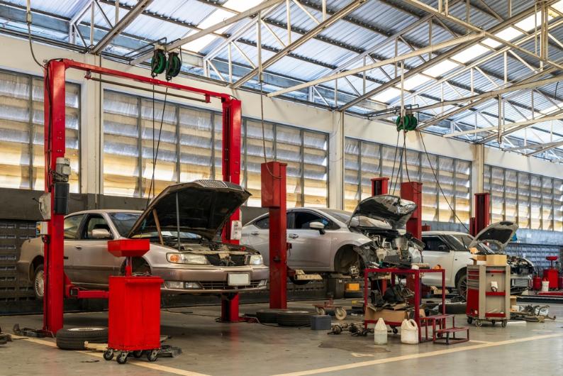 Cars in a auto repair garage. Universal auto body jigs streamline working with different car models.