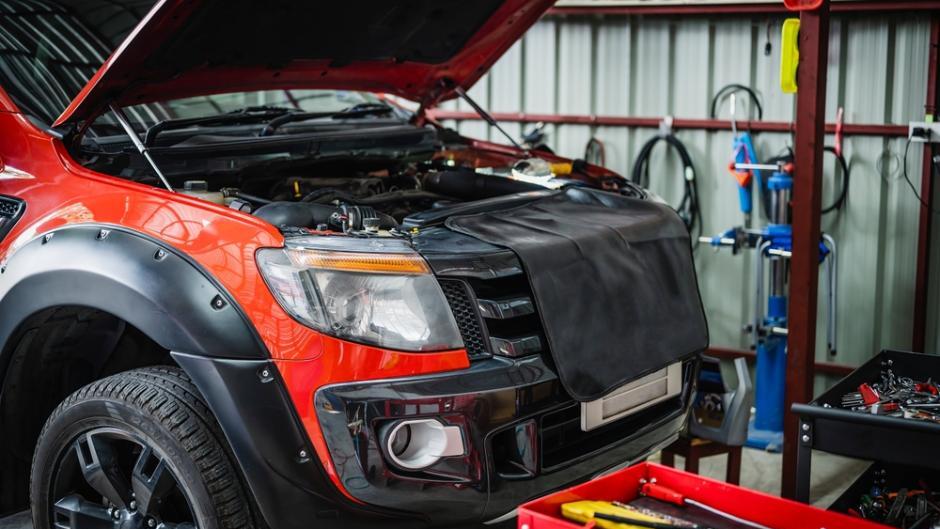 A car positioned in a modern collision repair bay set up for aluminum car body repair work
