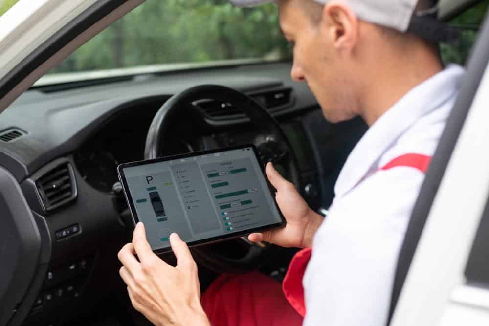 Technician using a diagnostic tool to check ADAS calibration system status