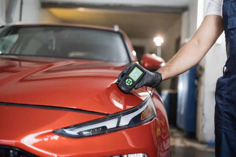 Technician verifying paint coating as part of a body shop quality control checklist
