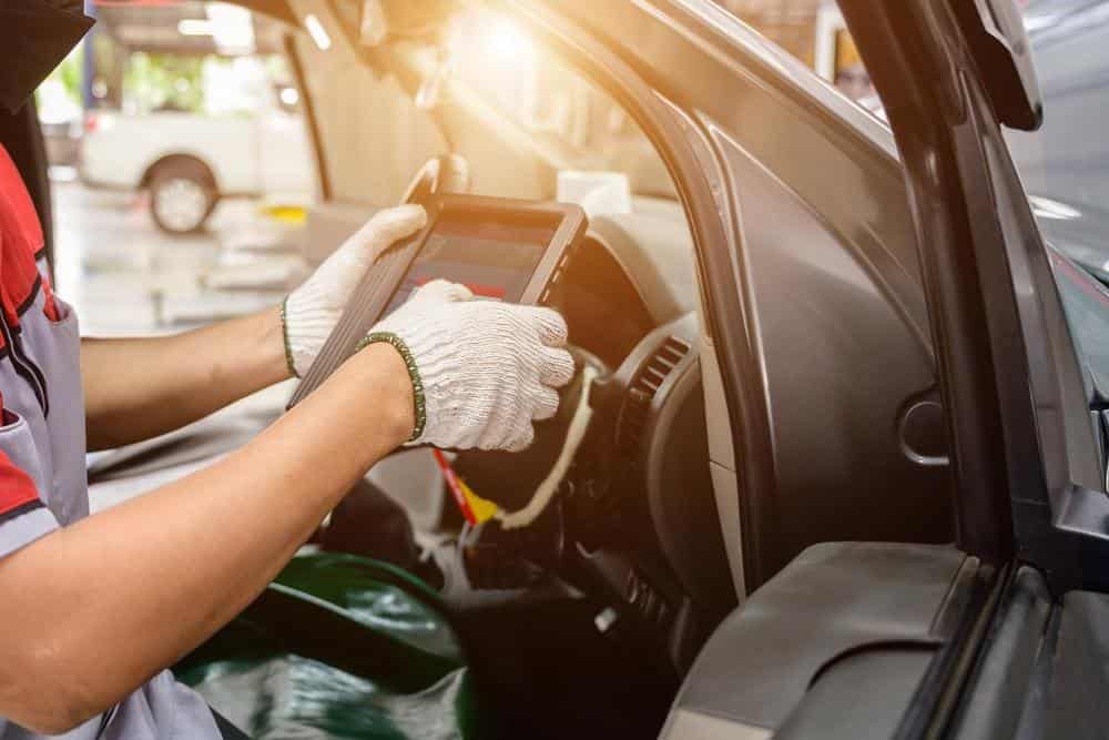 Technician using a digital tablet during a body shop quality control checklist review