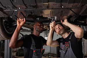 Two technicians inspecting vehicle structure at a body shop with I-CAR certification