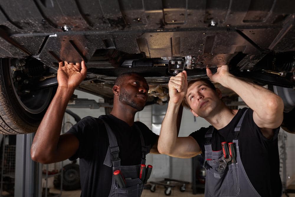 Two technicians inspecting vehicle structure at a body shop with I-CAR certification